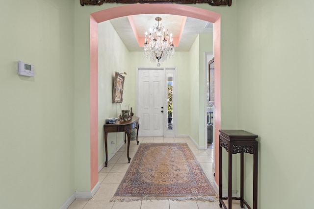 entrance foyer with baseboards, arched walkways, a notable chandelier, and light tile patterned flooring