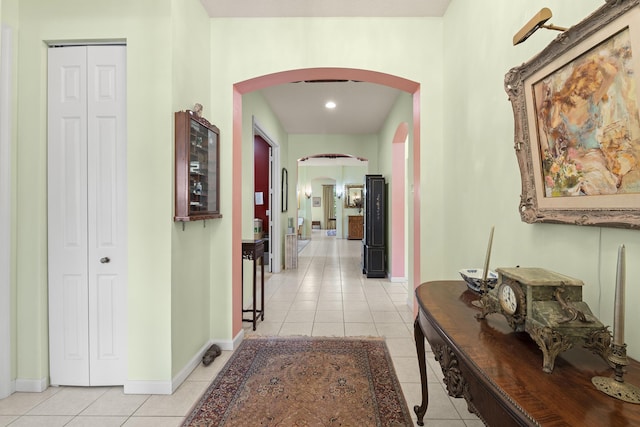 corridor featuring baseboards, light tile patterned floors, arched walkways, and recessed lighting