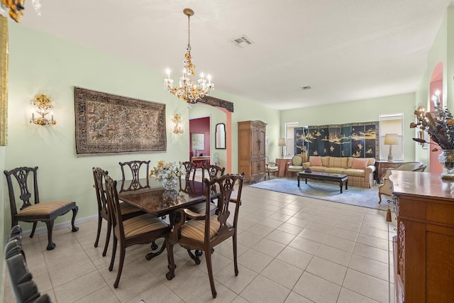 dining area featuring light tile patterned floors, a notable chandelier, arched walkways, and visible vents