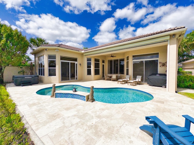 rear view of house featuring ceiling fan, a hot tub, and a tiled roof