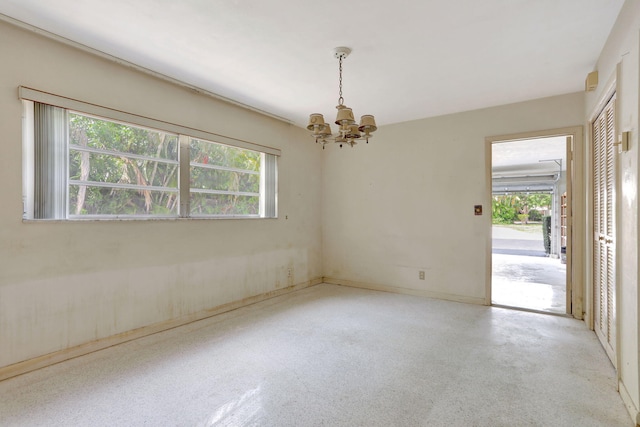 empty room featuring a wealth of natural light and a chandelier
