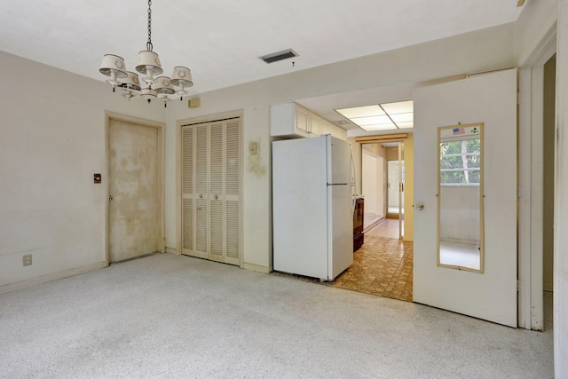 unfurnished room featuring visible vents, an inviting chandelier, and light speckled floor
