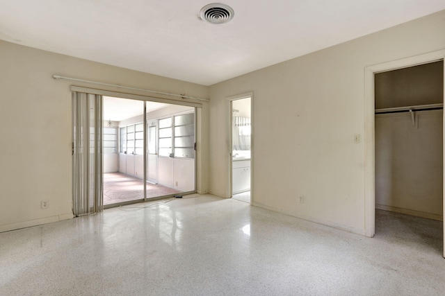 empty room featuring baseboards, visible vents, and speckled floor