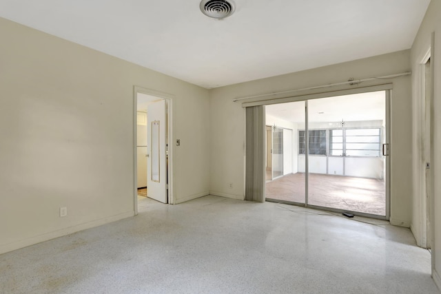 unfurnished room with baseboards, visible vents, and speckled floor