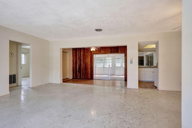 unfurnished room with visible vents, ceiling fan, speckled floor, and a healthy amount of sunlight