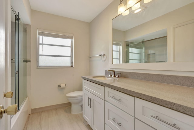 bathroom with vanity, baseboards, enclosed tub / shower combo, and toilet