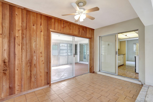 spare room featuring ceiling fan and wooden walls