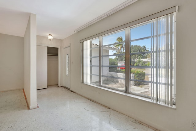 unfurnished bedroom featuring baseboards, a closet, and speckled floor