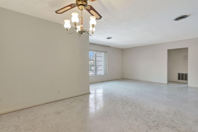 unfurnished room with visible vents, ceiling fan with notable chandelier, and speckled floor