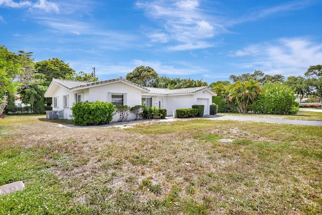 single story home with a front yard, stucco siding, a tiled roof, an attached garage, and driveway