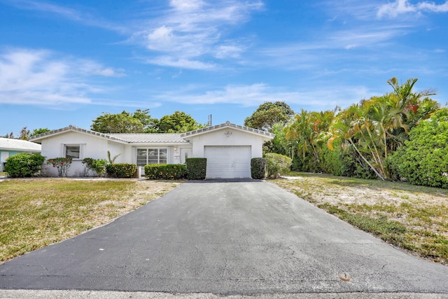 single story home with an attached garage, stucco siding, driveway, and a front yard