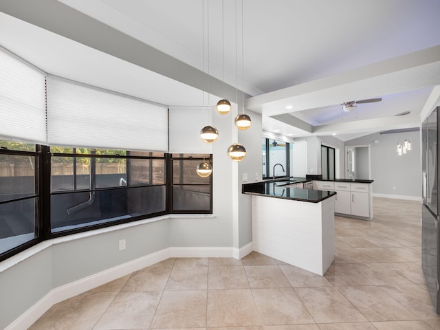 kitchen featuring light tile patterned flooring, dark countertops, a peninsula, and baseboards