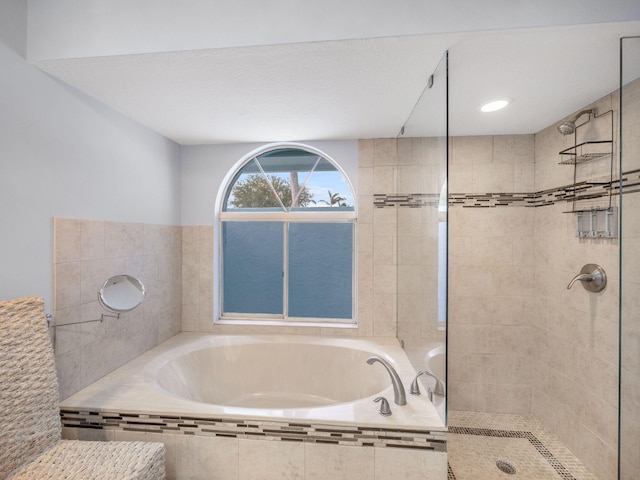 bathroom featuring a bath and tiled shower