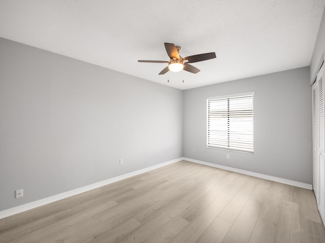 spare room featuring ceiling fan, baseboards, and light wood-style floors
