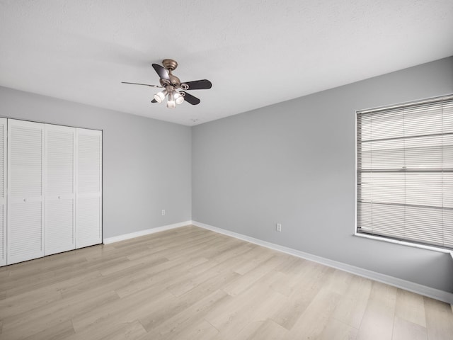 unfurnished bedroom with ceiling fan, a closet, light wood finished floors, and baseboards