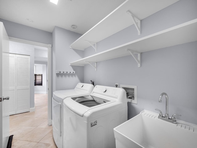 washroom featuring light tile patterned floors, washing machine and dryer, a sink, and laundry area