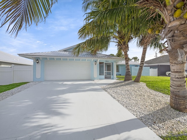 single story home with fence, concrete driveway, metal roof, an attached garage, and stucco siding