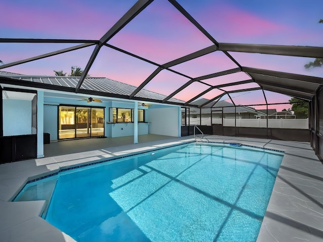 pool at dusk featuring a lanai, ceiling fan, a patio, and a fenced in pool