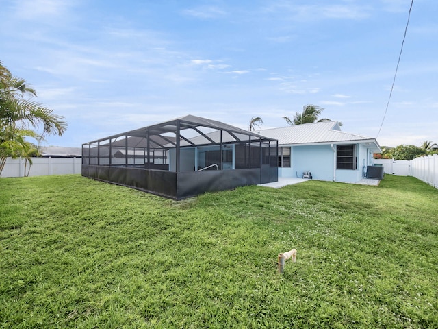 back of house featuring a lanai, a fenced backyard, central AC unit, and a yard