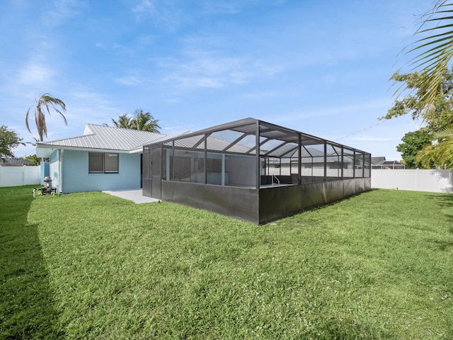 back of house with a lanai, a fenced backyard, and a yard