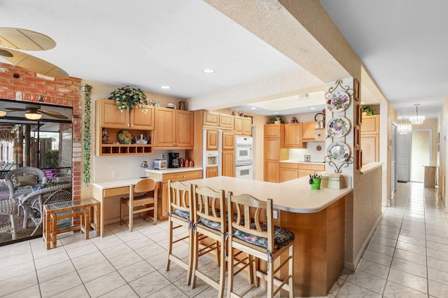 3163 NE 8th Ave, Boca Raton, FL 33431 - kitchen featuring light countertops, a peninsula, double oven, a kitchen bar, and recessed lighting