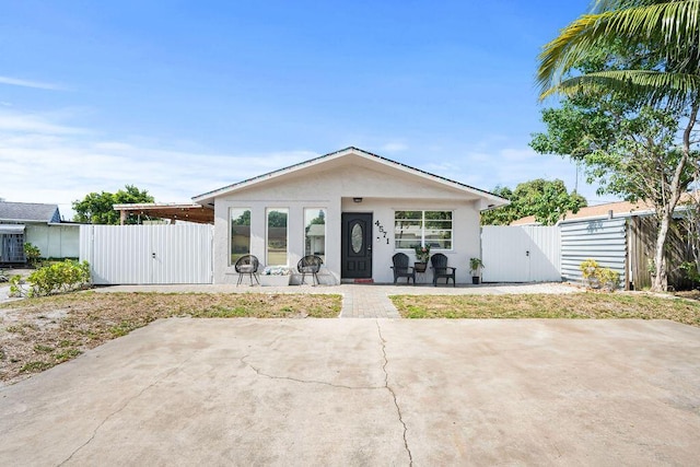view of front of home with fence, stucco siding, a patio area, and a gate
