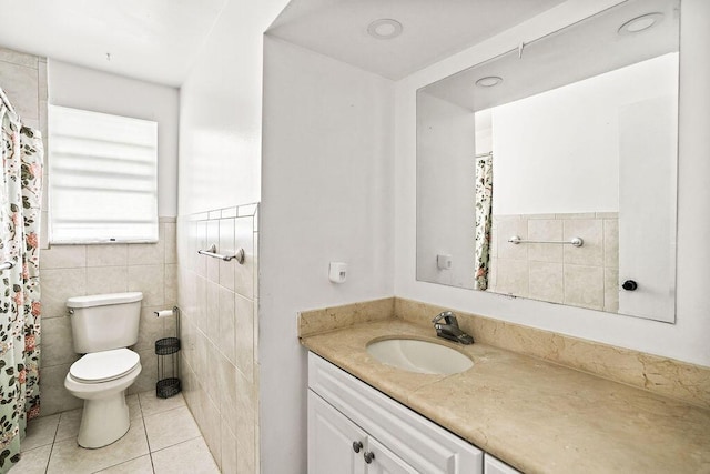 bathroom featuring tile walls, vanity, tile patterned floors, toilet, and wainscoting