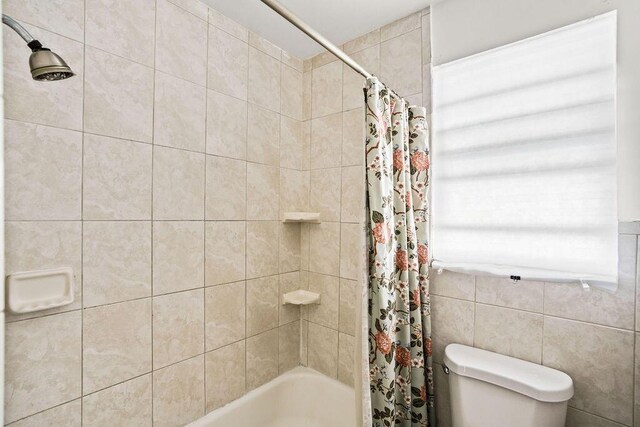 bathroom with shower / bath combination with curtain and toilet