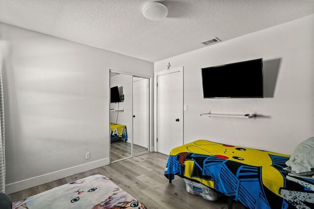 bedroom featuring visible vents, wood finished floors, a textured ceiling, and a closet
