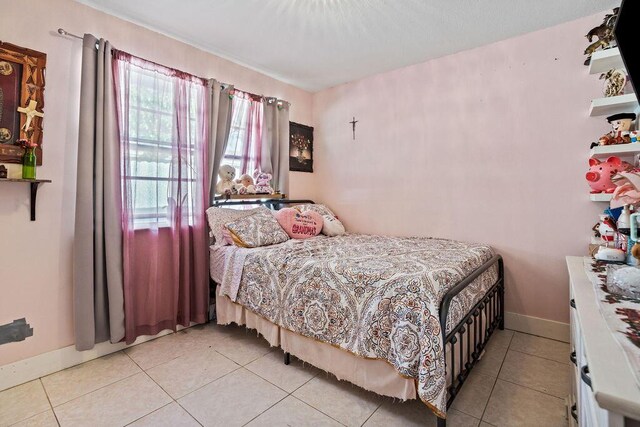 bedroom with baseboards and light tile patterned flooring