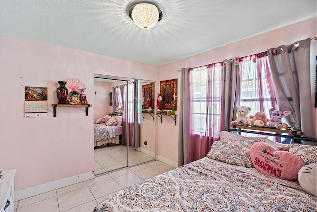 bedroom with light tile patterned floors, a closet, and baseboards