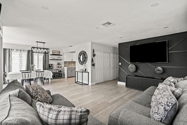 living area with visible vents, baseboards, and light wood-type flooring