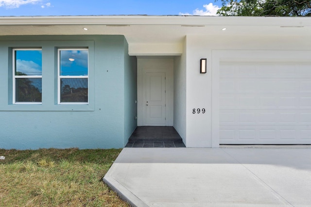 899 Gladiola Ave, Sebastian, FL 32958 - doorway to property featuring an attached garage, driveway, and stucco siding