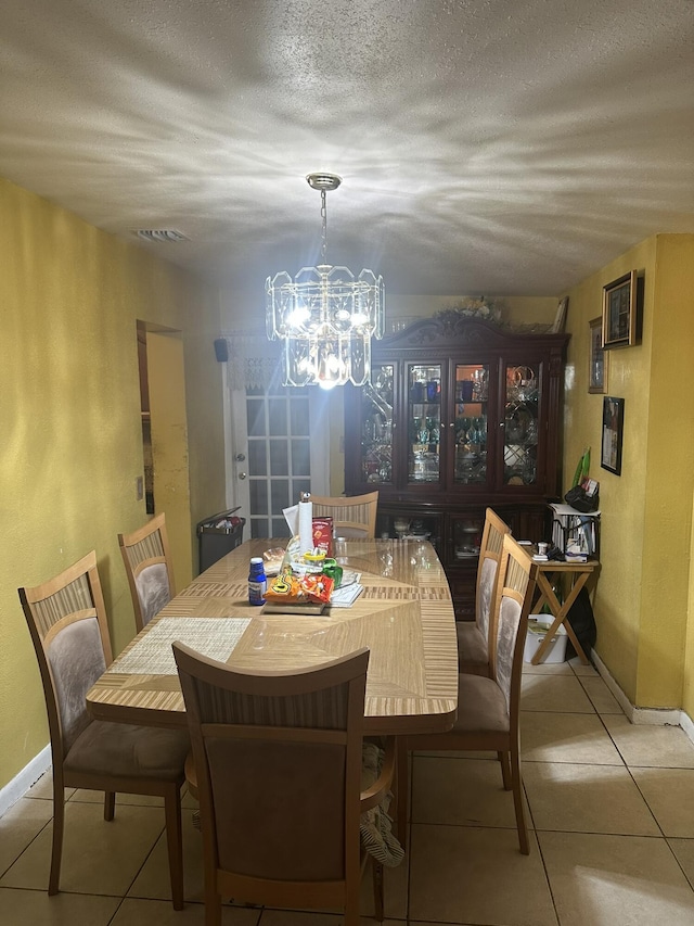 dining space featuring baseboards, an inviting chandelier, a textured ceiling, and tile patterned flooring