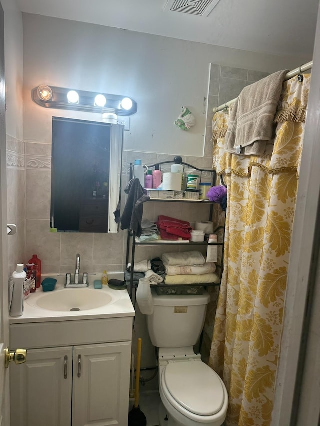 full bathroom with visible vents, toilet, tile walls, vanity, and backsplash