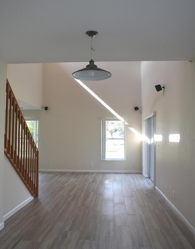 unfurnished living room featuring baseboards, wood finished floors, and a wealth of natural light