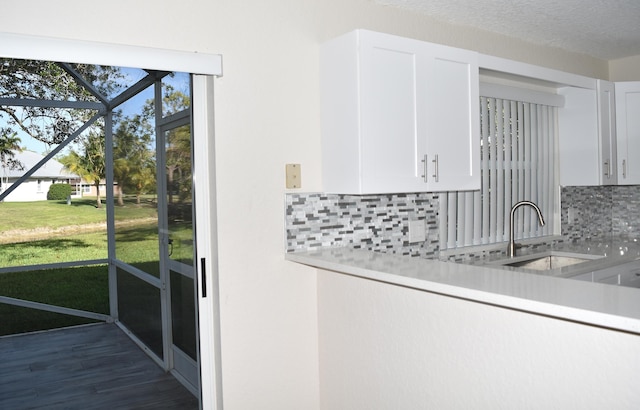 kitchen with decorative backsplash, white cabinets, a sink, light countertops, and wood finished floors