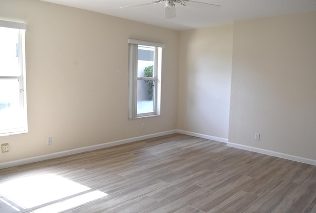 spare room featuring ceiling fan, light wood finished floors, and baseboards