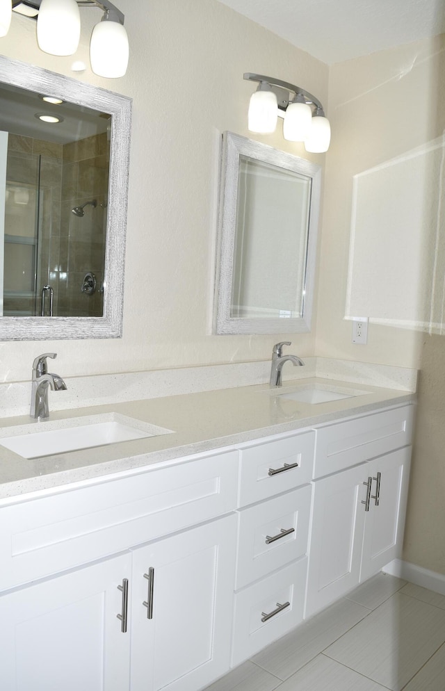 full bathroom featuring a stall shower, double vanity, a sink, and tile patterned floors