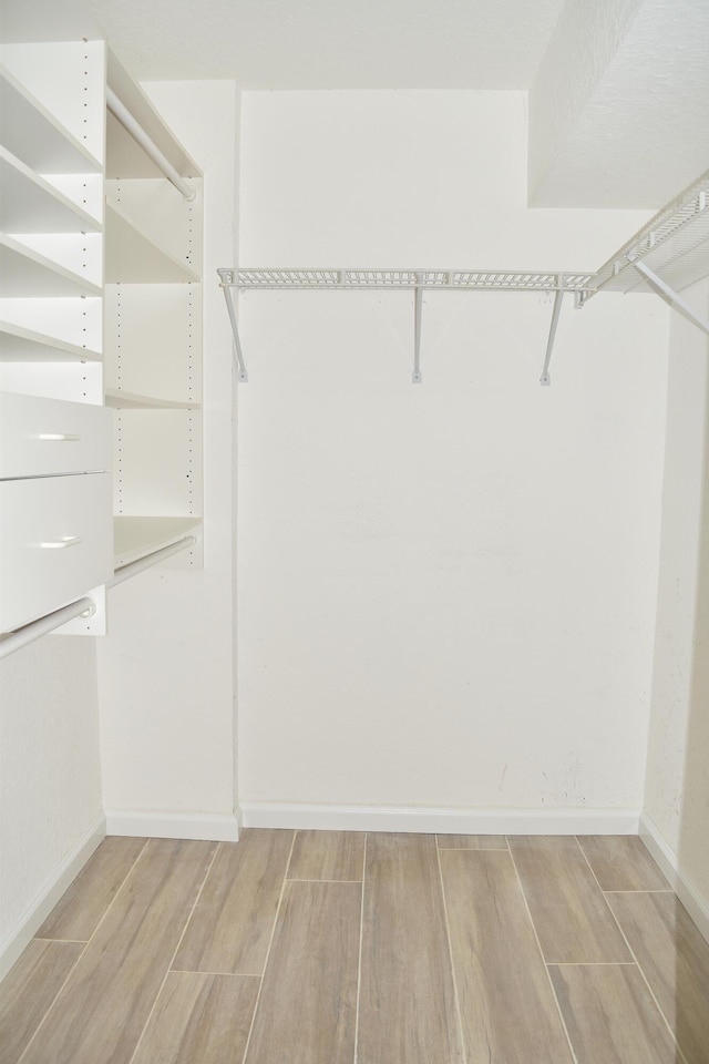 walk in closet with light wood-style flooring