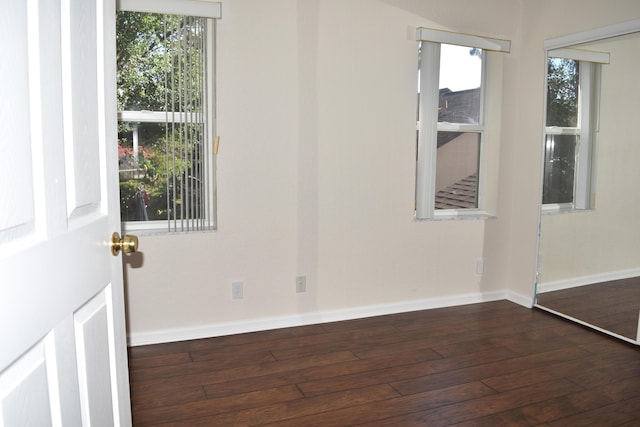 empty room with baseboards and dark wood-style flooring