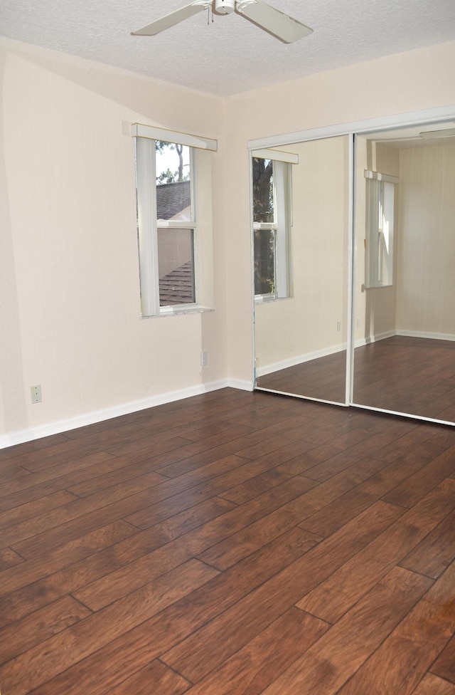 unfurnished bedroom featuring hardwood / wood-style floors, baseboards, ceiling fan, and a closet