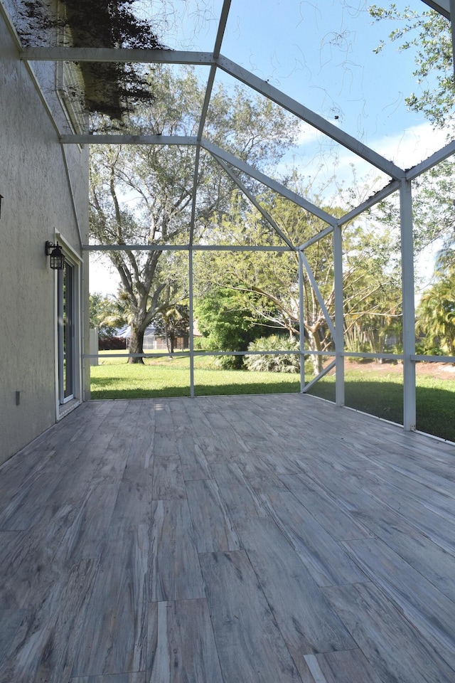 wooden deck with a lawn and glass enclosure