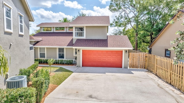 traditional home with stucco siding, roof with shingles, concrete driveway, and fence