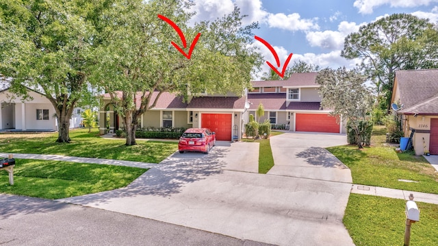multi unit property featuring stucco siding, a shingled roof, a garage, driveway, and a front yard