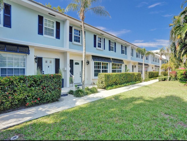 view of property with a front lawn and stucco siding