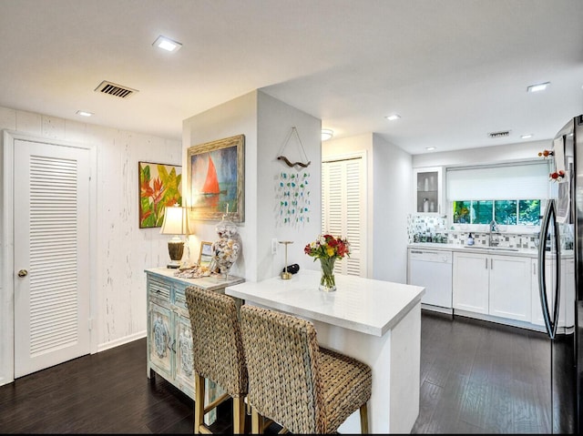 kitchen with visible vents, dark wood finished floors, dishwasher, a sink, and freestanding refrigerator