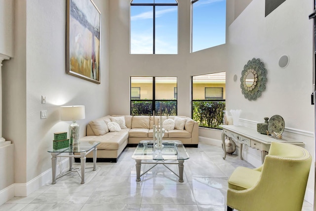 living area with baseboards, a high ceiling, and marble finish floor