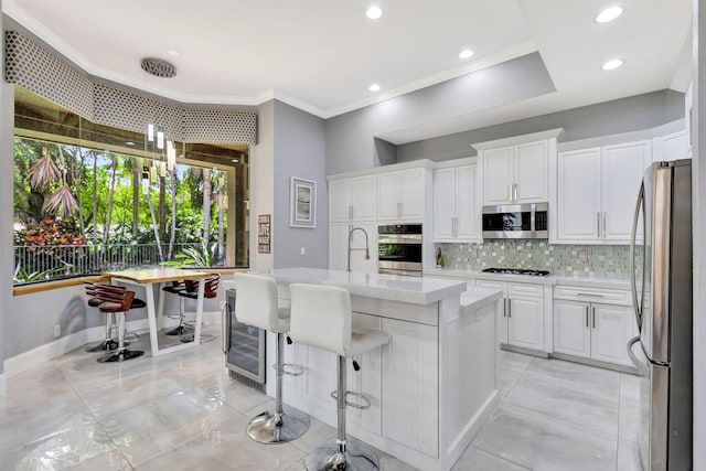kitchen with tasteful backsplash, crown molding, stainless steel appliances, light countertops, and wine cooler