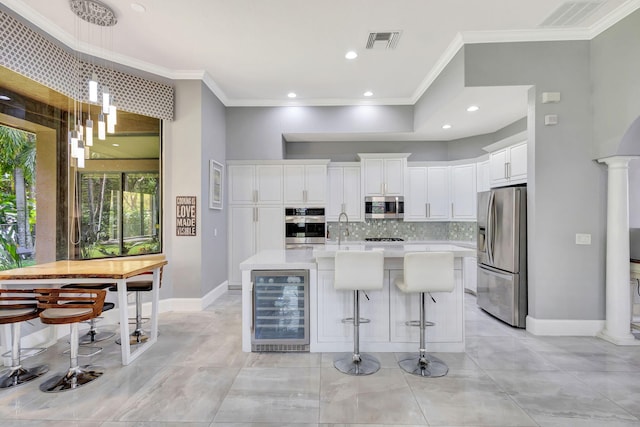 kitchen with decorative backsplash, appliances with stainless steel finishes, light countertops, visible vents, and wine cooler
